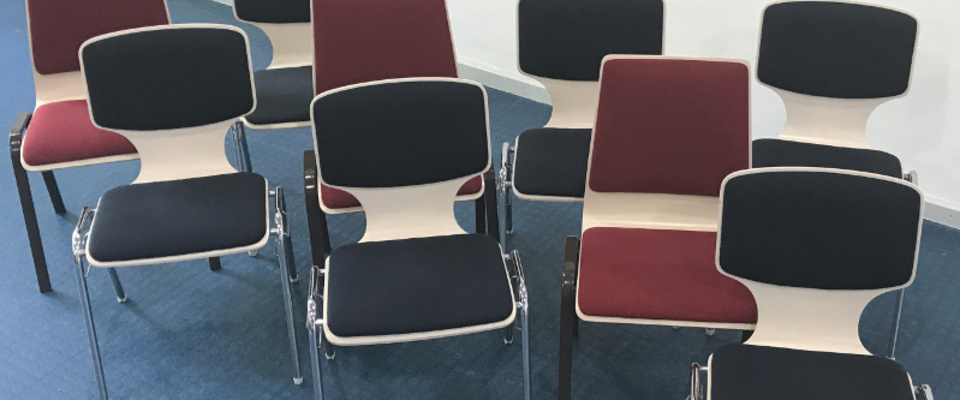 Anordnung von Stühlen mit roten und blauen Polstern