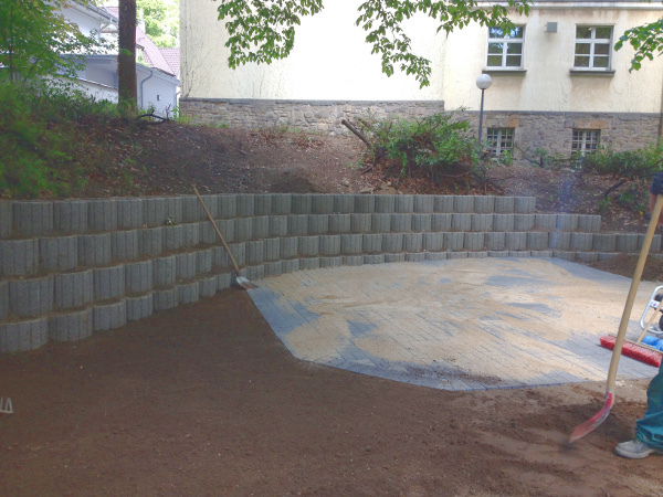 Abschluss der Hangbefestigung, die Terrassensteine werden mit Sand eingefegt.